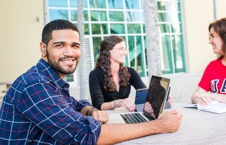 Student with a laptop sitting at a table